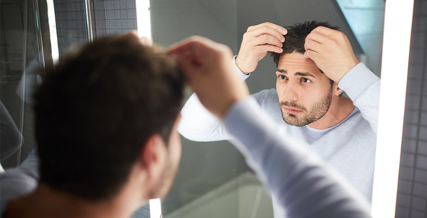 Man looking at scalp in mirror and asking himself "Is platelet-rich plasma injection therapy right for me?"